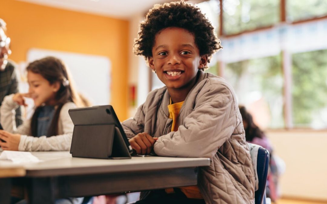 niño en clase con una tablet sonriendo